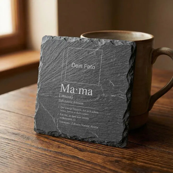 Gravierter Schiefer Untersetzer Mama-Lexikon-Design lehnt an Keramikbecher auf Holztisch im Tageslicht